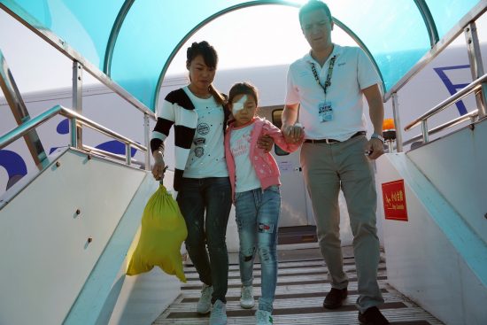 Xiu Ling descending the FlyingEye Hospital with her mother and Orbis staff member