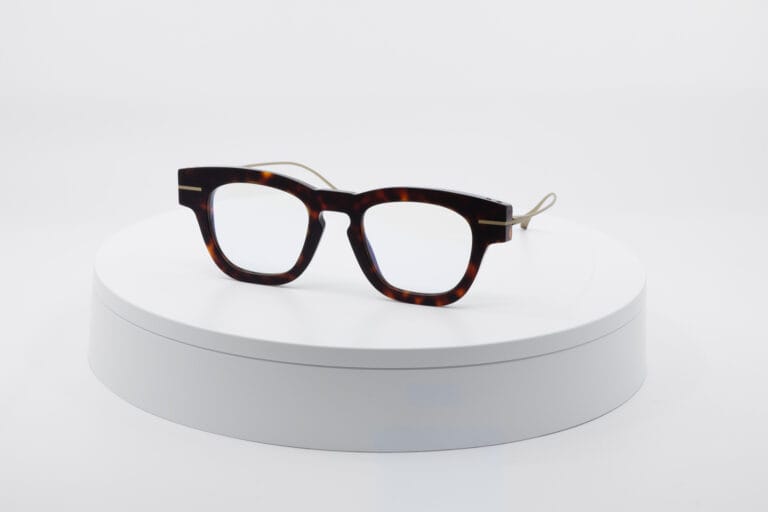 Tortoiseshell Eyeglasses with Light Beige Temples Resting on a White Round Display Pedestal Against a White Background.  | Eyestylist 14th May 2026