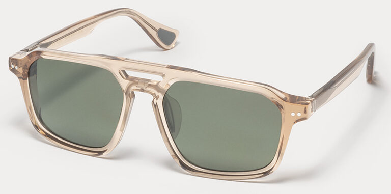 Beige Translucent Sunglasses with Dark Green Lenses Resting on a White Surface, Shown at an Angle.  | Eyestylist 12th May 2026