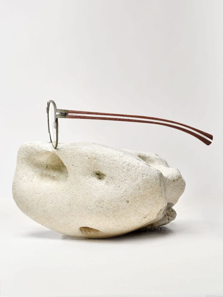image | Eyestylist Round Metal-framed Glasses with Wooden Temples Balanced on a Smooth White Rock. | Eyestylist 29th May 2026