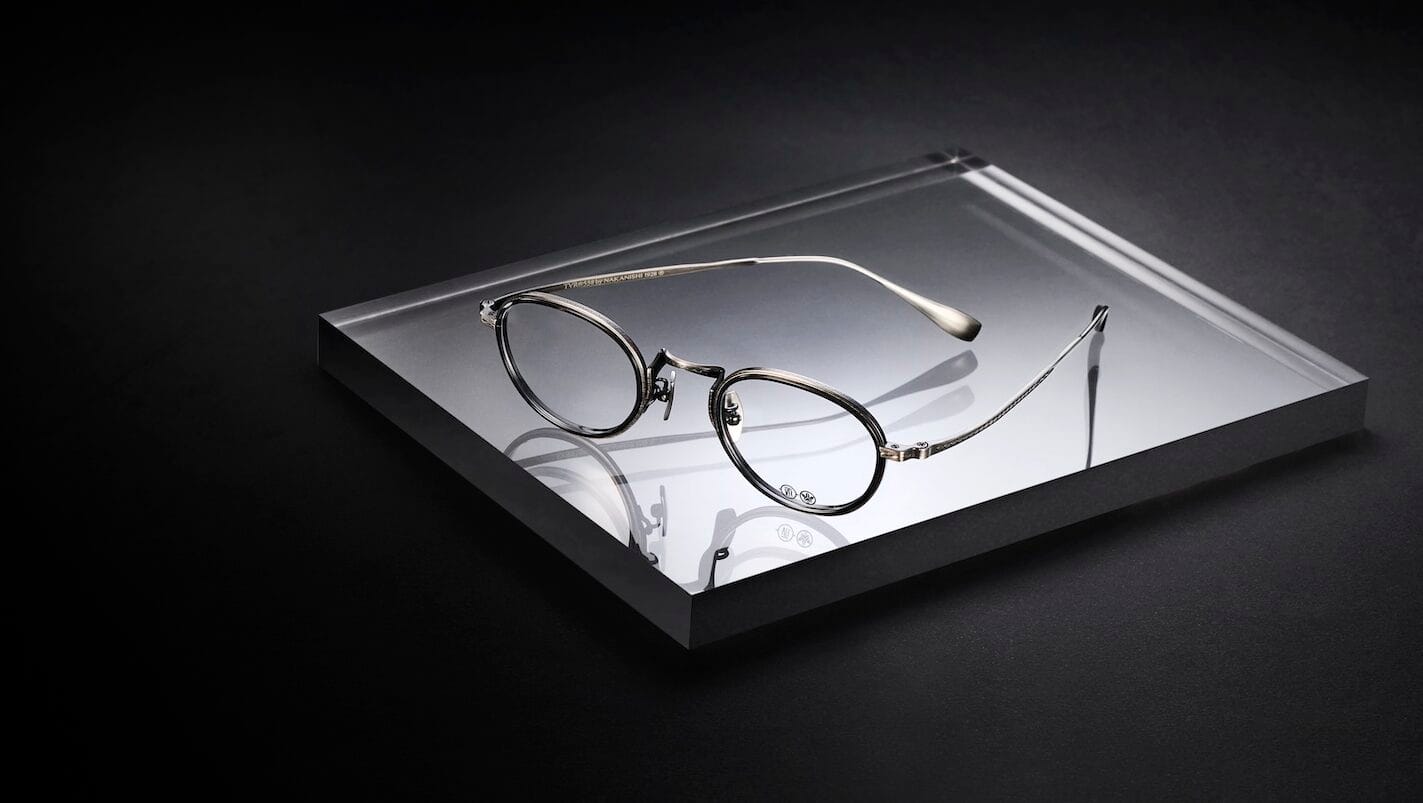 Eyeglasses displayed on a glass platform against a dark background in a product shot.