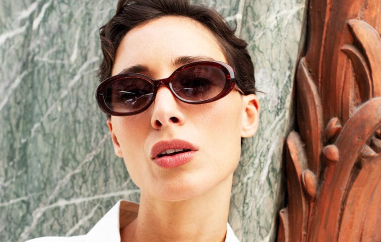 imagephp | Eyestylist Close-up of a Woman Wearing Oversized Brown Sunglasses Against a Marble Wall Backdrop. | Eyestylist 23rd June 2026